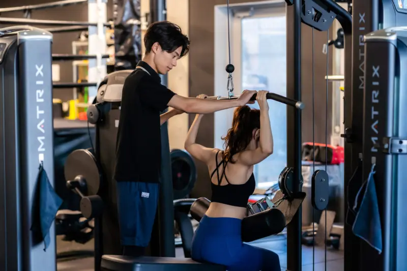 トレーナーの男性とトレーニング中の女性