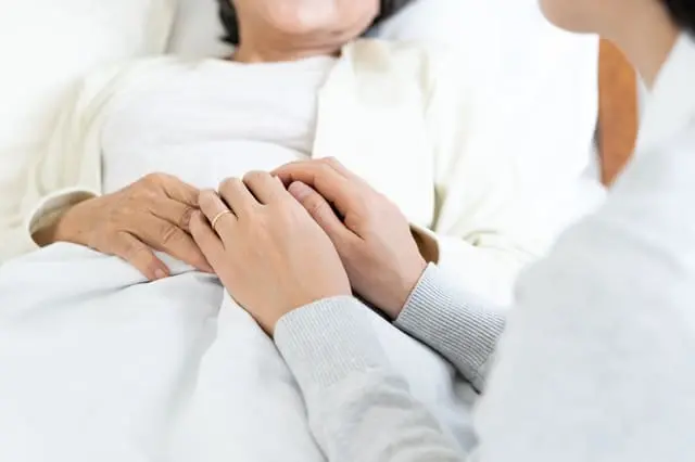 高齢者の手を握る人